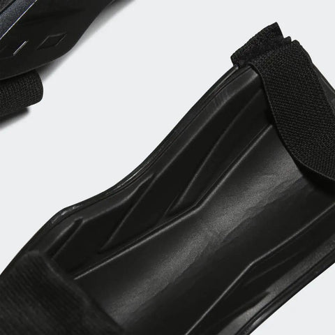 Close-up of Youth Shin Guards For Soft Ground Soccer Tiro Shield With EVA Backed Protection One Strap Quick Adjust Fit Ankle Sleeve Guard in black.