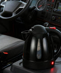 RigReady 24V 250W Portable Electric Kettle For Trucks And Rv on a console, black design, auto shutoff, 1 liter capacity.