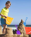 Child playing with orange bucket from 12 Pack 5 Inch Beach Buckets With Shovels Set For Kids Colorful Sand Pails Water Buckets Beach Toys
