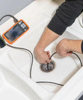 A plumber using Replacement 5.5 mm 4.9 Foot Armored Waterproof Inspection Snake With LEDs For Plumbers Borescope Cat No ET18 in a sink drain