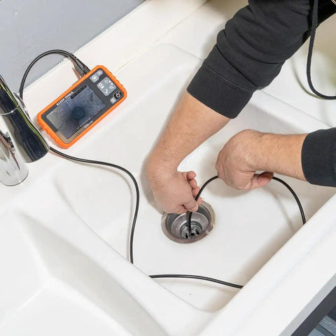 A plumber using Replacement 5.5 mm 4.9 Foot Armored Waterproof Inspection Snake With LEDs For Plumbers Borescope Cat No ET18 in a sink drain