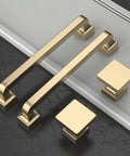 Gold cabinet handles and square knobs on black and white surface
