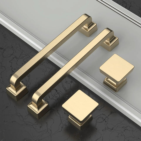 Gold cabinet handles and square knobs on black and white surface