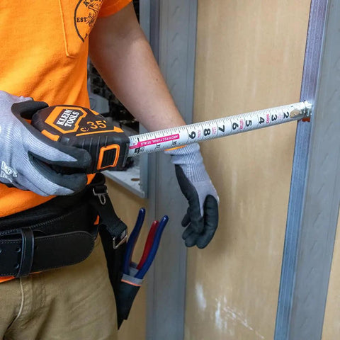 Person using 9235 Heavy Duty Magnetic Tape Measure With 16 Foot Reach, Double Hook, Double Sided Nylon Reinforced Blade, measuring wall
