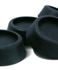 Close-up view of black anti-vibration pads for washing machines, showing four pads in a stack. Set of 8 included for noise reduction.
