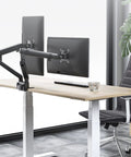 Adjustable Dual Monitor Arm Desk Mount With Smooth Mechanical Spring Height Tilt Swivel Rock Solid Clamp Base for dual screens on a wooden desk.