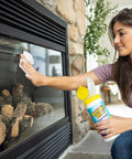 Front view of a woman wiping a glass fireplace door with Invisible Glass wipes, pre-moistened and streak-free.