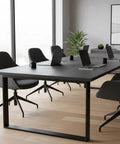 Modern conference room with heavy duty black table, ergonomic chairs, laptops, and greenery for professional use.