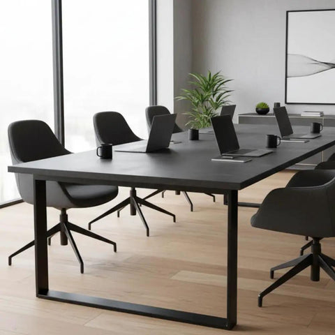 Modern conference room with heavy duty black table, ergonomic chairs, laptops, and greenery for professional use.