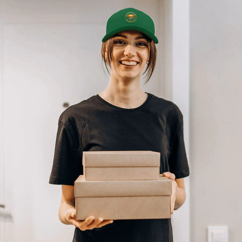 Person wearing Green Trucker Cap For Men And Women, Casual Sport Hat With Adjustable Buckle, holding boxes indoors
