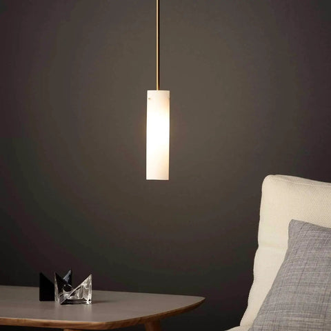 Hanging frosted glass light illuminating a modern setting with chair and table.