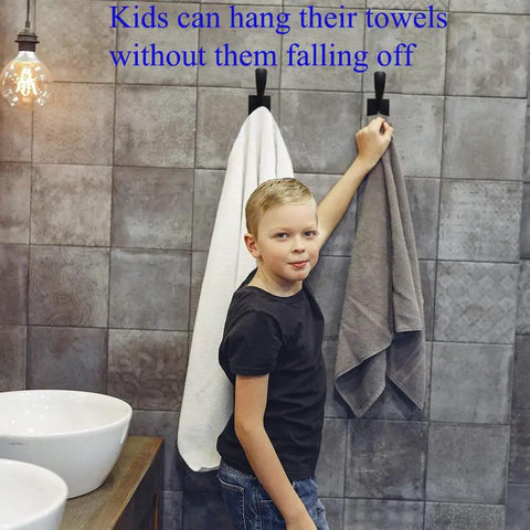 Child using Matte Black Double Towel Hooks Wall Mount Heavy Duty Coat Robe Clothes Hanger for hanging towels in bathroom.