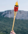 Two Pack Bamboo Tiki Torch Oil Lamp Set With Citronella Scented Fuel, Hand Woven Rattan Design in use against mountain backdrop