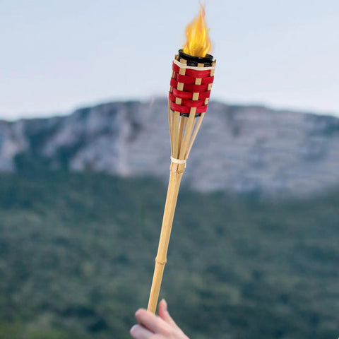 Two Pack Bamboo Tiki Torch Oil Lamp Set With Citronella Scented Fuel, Hand Woven Rattan Design in use against mountain backdrop