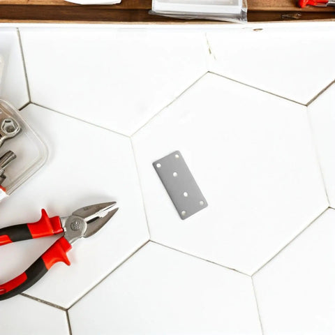 Rust Resistant Stainless Steel Corner Brackets Set Of 10 Flat Mending Plates with tools on white hexagonal tiles.