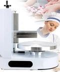 Top Shelf Buttercream Smoothing Machine With 35CM Adjustable Turntable And Thin Metal Blade, side view with decorated pastries in background.