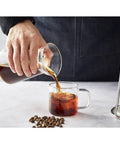 Person pouring cold brew from a glass carafe into a clear cup using the 600 mL Detachable Cold Brew Coffee Dripper Tower.