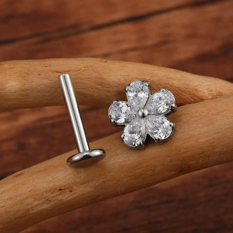 Top Shelf 16G Flower Cartilage Piercing Jewelry In ASTM F136 Titanium Hypoallergenic Flat Back Studs, silver flower stud earring on a wooden surface.