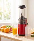 Sleek Red Masticating Cold Press Juicer With Extra Wide Feed Opening For Whole Fruits And Veg, High Yield Electric Juicing Machine Preserves Nutrients For Healthy Enthusiasts At Home on a kitchen table with juice and fruits.