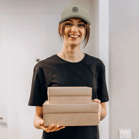 Person wearing lightweight low profile trucker hat for men apricot washed cotton dad cap with adjustable strap, smiling indoors.