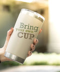 Person holding a 20 oz tumbler with 'Bring your own CUP' text outdoors, suitable for Elastic Sublimation Tumbler Holder Ring Bands usage.