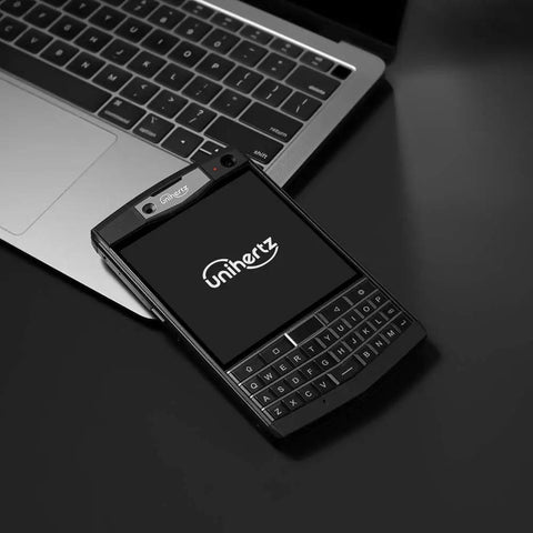Tough As Nails Rugged QWERTY Smartphone Powered By Rock Solid Android 10 Platform beside a laptop on a black surface.