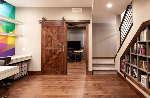 Home office with a wooden barn door featuring vintage solid brass pulls in antique copper finish for rustic charm and functionality.