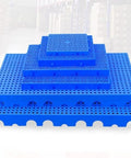 Stacked blue lightweight interlocking plastic pallets with ventilated grid surface for storage