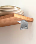 Ten Pack 304 Stainless Steel Shelf Brackets 90 Degree L Shaped Support installed under a wooden shelf holding plates on a wall.
