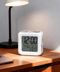 Solid Pick Straight Up Quiet Digital Cube Alarm Clock Country Blue Floral Pattern With Vintage Stamp Letters Comfortable Silicone Buttons Warm Nightlight Snooze Feature And Clean Time Date Temperature Display on wooden desk next to lamp.