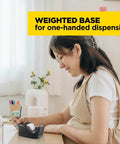 Woman using Deluxe Black Desktop Tape Dispenser With Weighted Non Skid Base For One Handed Dispensing Holds 1 Inch Core Tape on desk