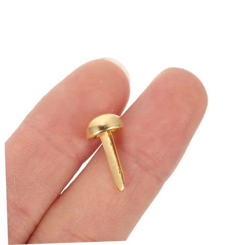 Close-up of a single golden decorative tack held between fingers, part of the 100 Piece Decorative Tacks And Miniature Nails For DIY Crafting Go To Fasteners Jewelry Box Projects Paper Clips For Photos Cards And More Durable Wear Resistant Brads For Scrapbooking And Home Decor set.