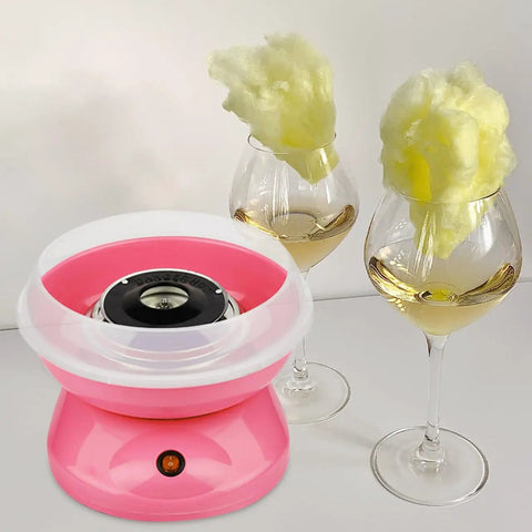 Pink cotton candy machine with white plastic shield next to glasses of cotton candy on sticks