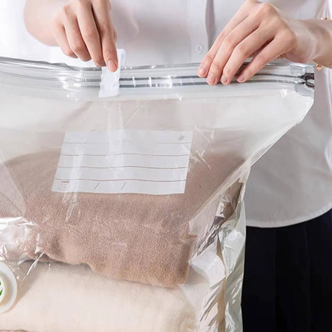 Person sealing a vacuum bag with 30 Pack Vacuum Storage Bag Sealing Clips Quick Snap Zipper Grips, preserving clothes.