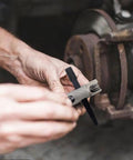Grease fitting replacement tool with knurled metal handle installing a black zerk into a rusted vehicle hub
