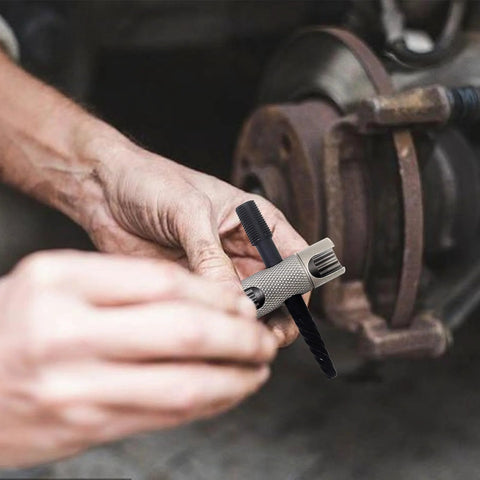 Grease fitting replacement tool with knurled metal handle installing a black zerk into a rusted vehicle hub