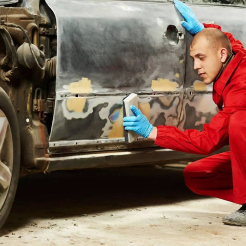 Person using Jhknnk 5pc Premium Dry Wet Sandpaper Set Featuring Tear-Resistant Silicon Carbide Sheets for metal sanding on a car.
