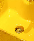 Close-up of the gold bathroom ceramic vessel sink bowl, highlighting the polished drain in a vibrant yellow sink.