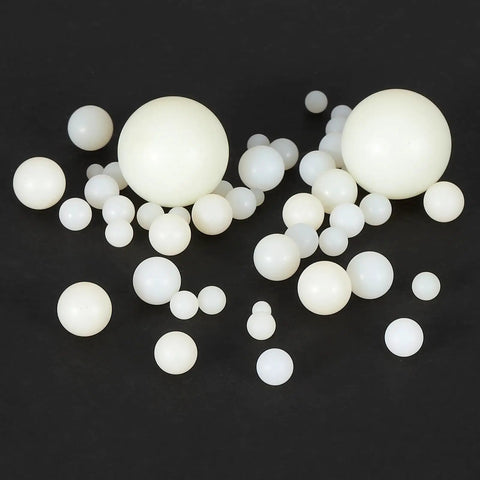 20 Pack White Nylon Bearing Balls Three Quarter Inch G2 precision spheres scattered on black background, showing different sizes.