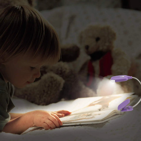 Child reading under Kids Clip On Reading Light 3 Pack Battery Operated Dimmable Lamp With 12 CR2016 Batteries Included Flexible 360 Degree Neck For Bedtime Reading Kid Friendly LED Low Heat Soft Light For Cozy Nights In Bed