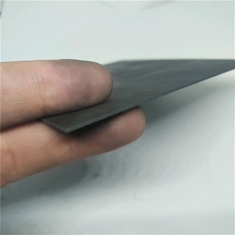 Person holding a high temp graphite plate for electrodes and pyrolysis blocks, highlighting its compact structure and low porosity material.