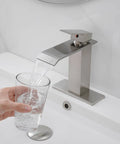 Swanky Brushed Nickel Waterfall Bathroom Faucet With Single Handle For Modern Sinks And 1 Or 3 Hole Installations, pouring water into glass