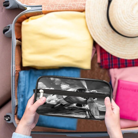 Travel Toiletry Bag For Men Women Kids Waterproof Dopp Kit Organizer held over packed suitcase with clothes and hat