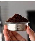 Premium Titanium Portafilter Basket 58.5mm holds 18 to 20 grams with ground coffee, ideal for espresso preparation.