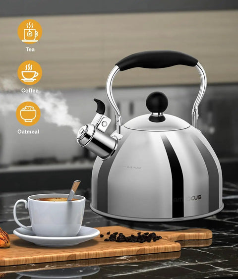 Stainless Steel 2 Quart Whistling Tea Kettle For Stovetop With Ergonomic Folding Handle shown next to coffee cup on countertop.