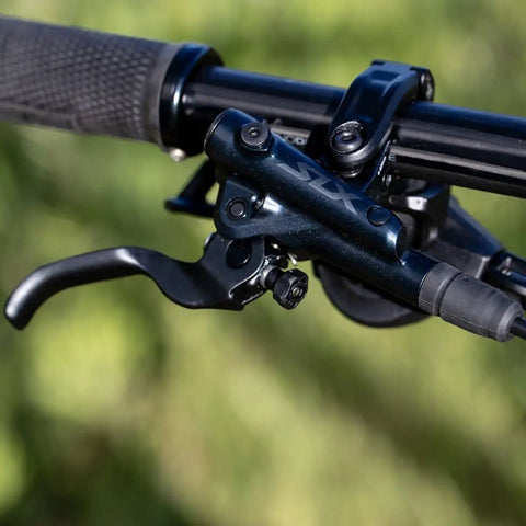 Close-up of M7100 SLX Hydraulic Disc Brake Left Front Post Mount 2 Piston Caliper showing lever and mounting on bike handlebar.