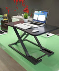 Portable Sit Stand Desk Converter With Heavy Duty Dual Tray Ergonomic Stand on a green desk holding laptop and keyboard.