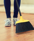 Person using 3 Pack 54 Inch Heavy Duty Rugged Outdoor Brooms With Four Layer Stiff Bristles For Pro Grade Commercial Indoor Outdoor Use In Courtyard