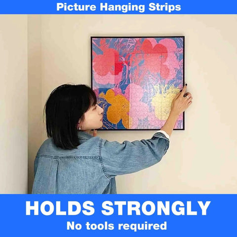Woman hanging art using Heavy Duty Hook And Loop Tape 4x8 Inches, 6 Pairs Self Adhesive Interlocking Strips for Picture Hanging