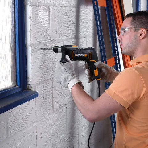 User operating a Heavy Duty 600 Watt Impact Drill Driver With 13 Mm Keyless Chuck and Variable Speed Control on a concrete wall.